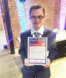Image of Sean looking proud, holding a diploma