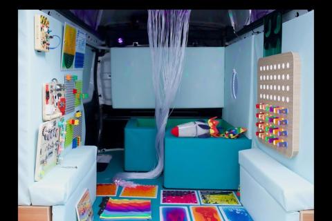 A sensory room with a ball pit, textured pads on the floor and wooden/plastic toys on the walls