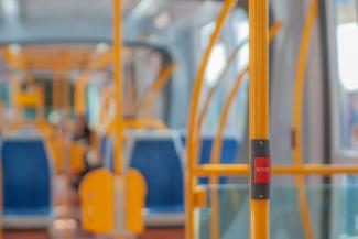 Inside of a brightly lit bus with seats, poles and a stop button. 